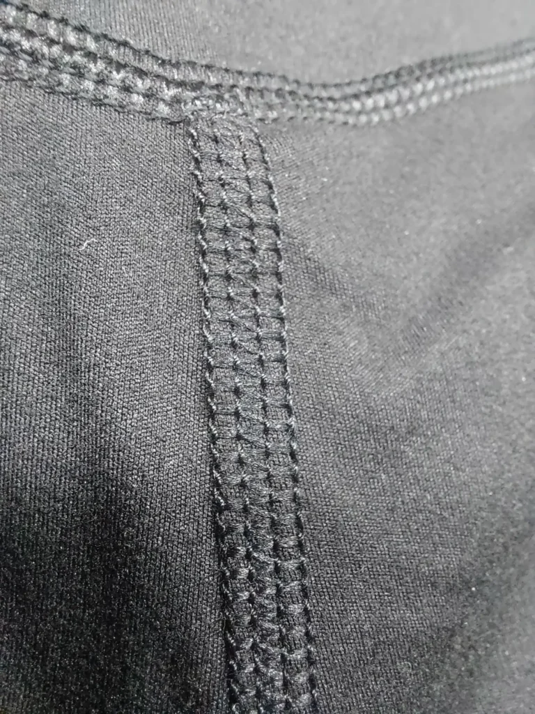 Close-up of 4-needle flatlock stitching on activewear leggings — GYMHUR factory, Sialkot