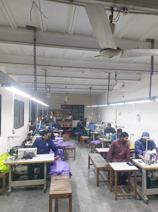 Interior of a textile manufacturing facility showing a fully staffed stitching department and high-volume production line